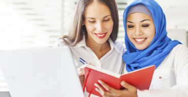 Cultura na tradução: mulher muçulmana mostrando um livro vermelho para tradutora